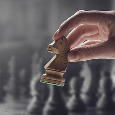 Chess player holding a piece and chess game on the chessboard in the background, game tournament concept