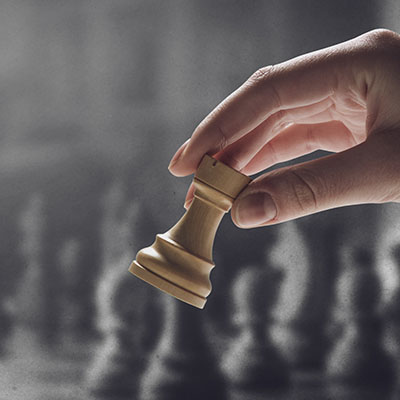 Chess player holding a piece and chess game on the chessboard in the background, game tournament concept