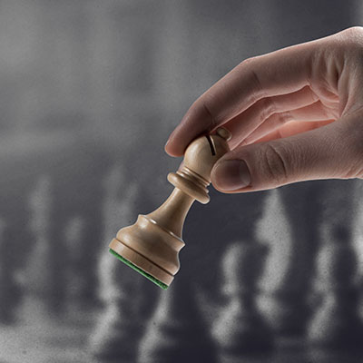 Chess player holding a piece and chess game on the chessboard in the background, game tournament concept